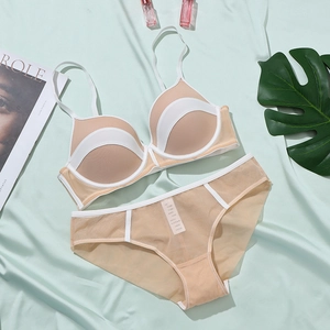 Flat lay of breathable nude mesh lingerie set with white trim on green satin background