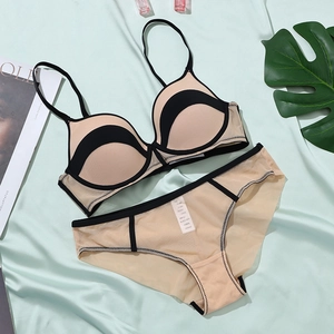 Flat lay of beige mesh lingerie set with black contrast trim on silk background
