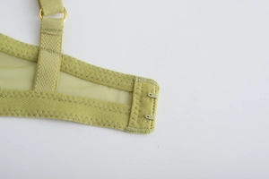 Detail of avocado green mesh bra showing the double hook-and-eye closure and gold metal rings