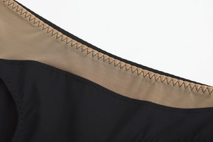 Detailed close-up of zigzag stitching and mesh fabric on black seamless lingerie