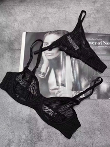 Detail of sheer black lace lingerie set with mesh floral patterns on grey background