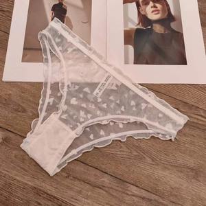 Detail shot of white mesh lace panties with heart patterns and ruffle edges on wood texture