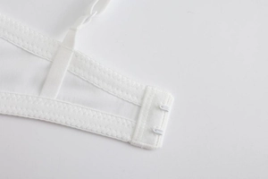 Detail of white mesh bra back closure featuring secure double row metal hooks and fine stitching