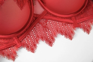 Macro detail of red silk satin bra with delicate floral eyelash lace and underwire