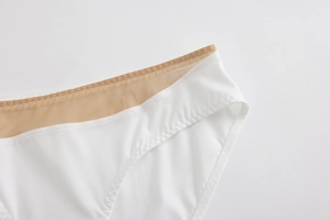 Macro detail of white seamless panties featuring sheer mesh waistband and zigzag stitching