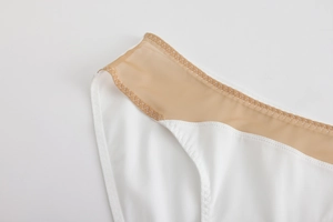 Close-up of seamless white mesh bra with refined zigzag stitching and elastic waistband