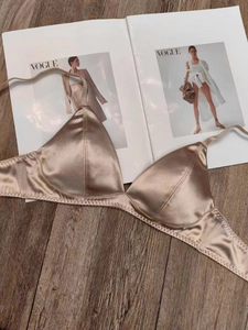 Detailed view of champagne satin wireless bra on a vintage wood and magazine background