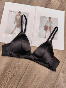 Close-up of black satin triangle bra with thin straps on a Vogue magazine background