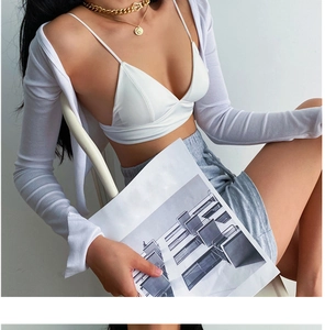 Détail d'un cardigan blanc en maille côtelée sur un soutien-gorge avec collier doré superposé