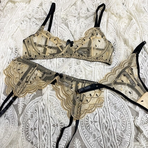 Champagne lace lingerie set with black embroidery and garter belt on white lace background