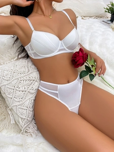 Detailed view of white lace lingerie set with underwire bra and high-cut thong on soft rug