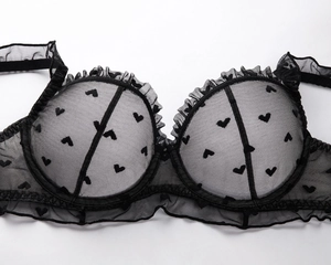 Detail of black mesh lace bra with flocked hearts and ruffled trim in French style