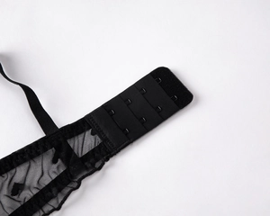 Detail view of black lace bra featuring three-row hook closure and heart mesh pattern
