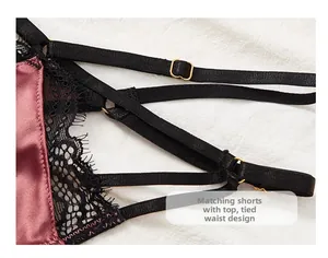 Dettaglio di lingerie in raso bordeaux con pizzo nero e fibbie dorate regolabili