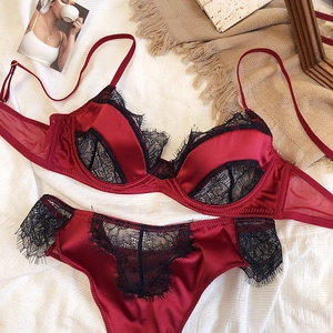Detail of red satin and black eyelash lace lingerie set on white linen fabric