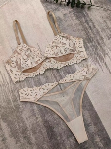 Dettaglio completo di set intimo in pizzo bianco con ricami floreali e spalline sottili