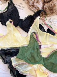 Flat lay of sheer mesh lace bras in black, yellow, and green with ruffled trims