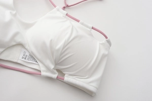 Detailed macro view of white wireless bra fabric with pink straps and brand wash label