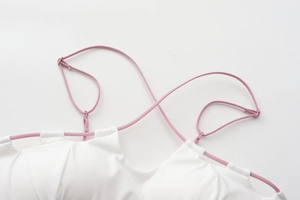 Close-up of white wireless bra with pink cross-back straps showing fabric texture