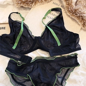 Detail of dark blue sheer mesh lingerie set with green wavy trim and thin straps