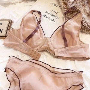 Detailed macro view of beige mesh lace lingerie set with underwire cups on white linen