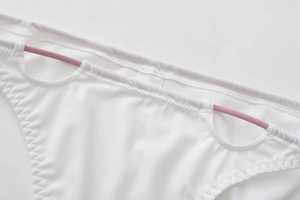 Detailed close-up of white lingerie with pink elastic side straps and fine stitching