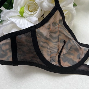 Detail of sheer black mesh bra with leopard print lining and elegant floral background
