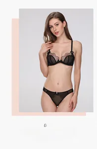 Detail of sheer black lace bra and panty set with delicate bow accents on a model