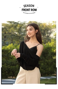 Outdoor shot of a model in a black long-sleeved sheer top with beige high-waist wide trousers