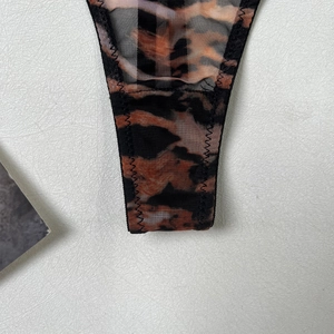 Detail of leopard print sheer mesh fabric with reinforced black zigzag stitching edges