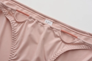 Detail of pink seamless panties with wavy stitched edges and lace-up side design