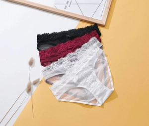 Detail view of lace panties in black, red, and white with floral embroidery and bows