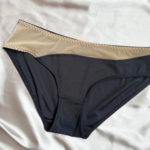 Detail of black seamless low-rise briefs featuring mesh panels and fine zigzag stitching