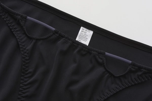 Detail of seamless black low-waist panties showing cotton lining and fabric wash label