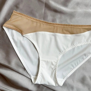 Detail of white seamless briefs with beige mesh stitching and zigzag elastic seam