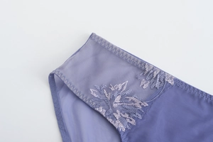 Gros plan sur le mesh semi-transparent avec broderie florale violette et bordure ondulée