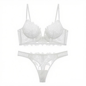 Detailed close-up of white floral lace embroidery on sheer French style bra and thong set