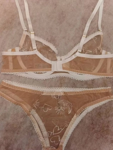Gros plan de la broderie soleil et lune blanche sur un ensemble de lingerie en dentelle