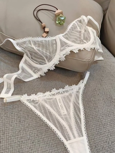 Detailed view of white floral embroidery lace bra and matching thong with size tag
