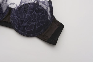 Detailed macro view of dark purple eyelash lace bra showing floral patterns and satin wings