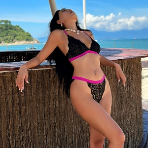 Detail view of black lace lingerie with pink trim on a beach background