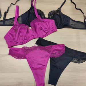 Detail view of lace trim and sheer mesh wings on deep rose and black lingerie sets