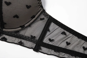 Detail of black mesh bra showing heart pattern flocking and fine seam craftsmanship