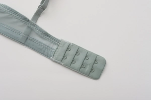 Detail of adjustable straps and four-row back closure on green lace mesh bra