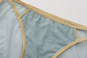 Detail of light blue mesh fabric with yellow elastic trim and zigzag stitching on bra