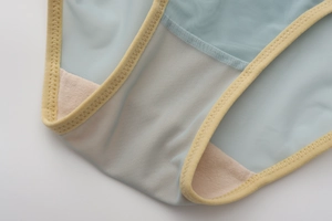 Detail of soft mesh fabric and fine stitching on the inner crotch of light blue panties