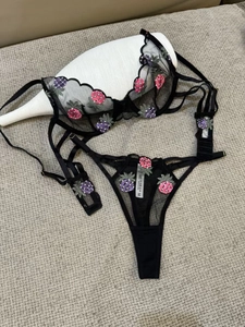 Detail of black lace lingerie set with pink pineapple embroidery and adjustable straps