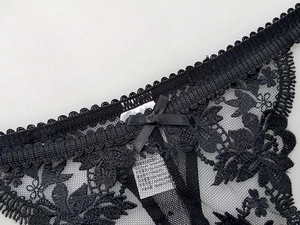 Detailed close-up of black floral lace underwear with delicate mesh and silk bow detail
