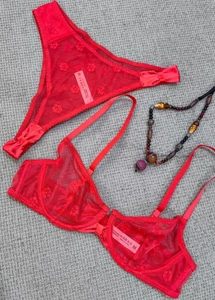 Detailansicht eines roten Netz-Dessous-Sets mit Blumenstickerei und Satinschleife