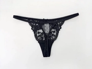 Detail of black lace thong featuring delicate floral embroidery and thin elastic straps